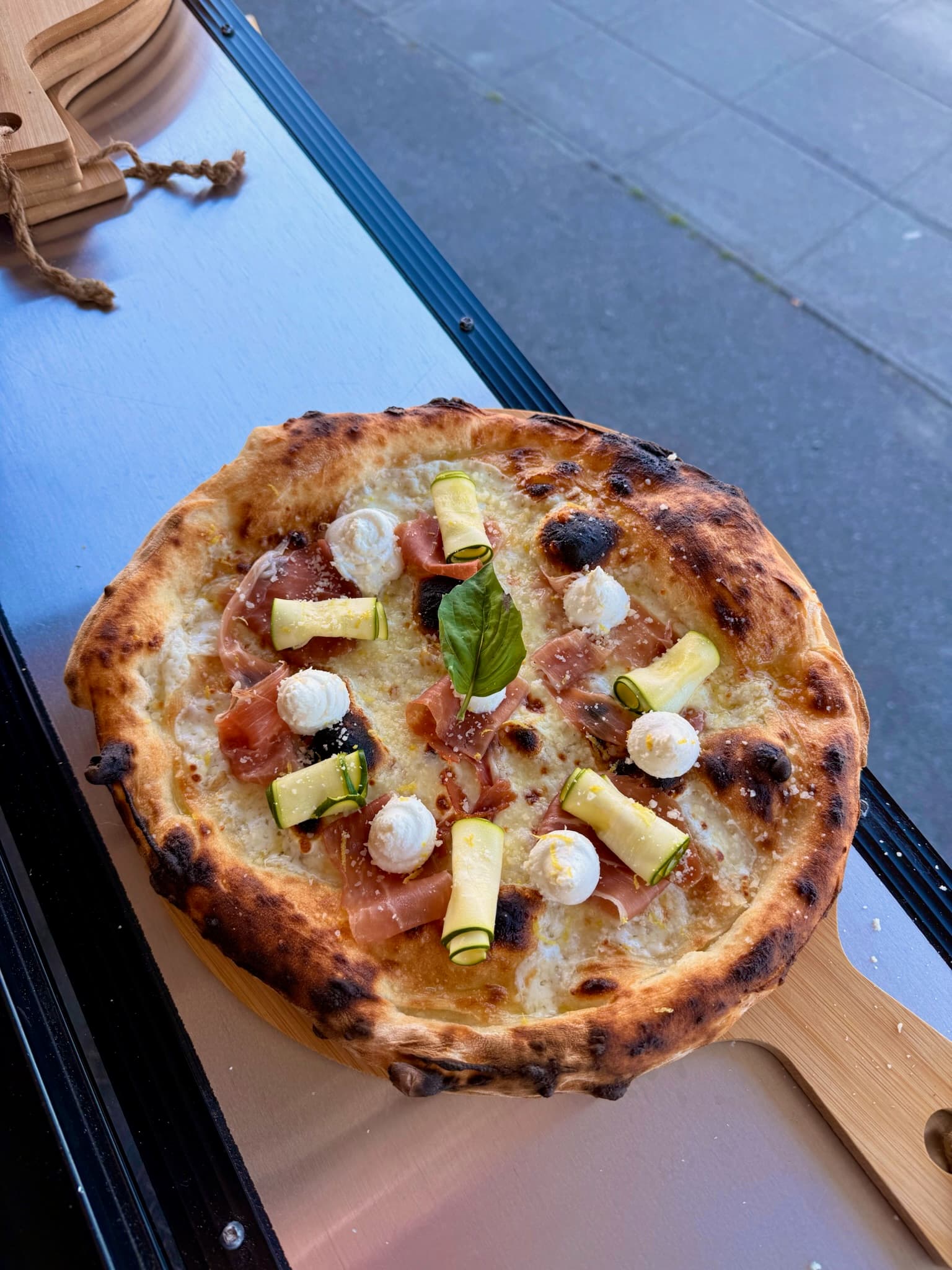 Artisan pizza cooking over live fire with bubbling cheese and fresh toppings