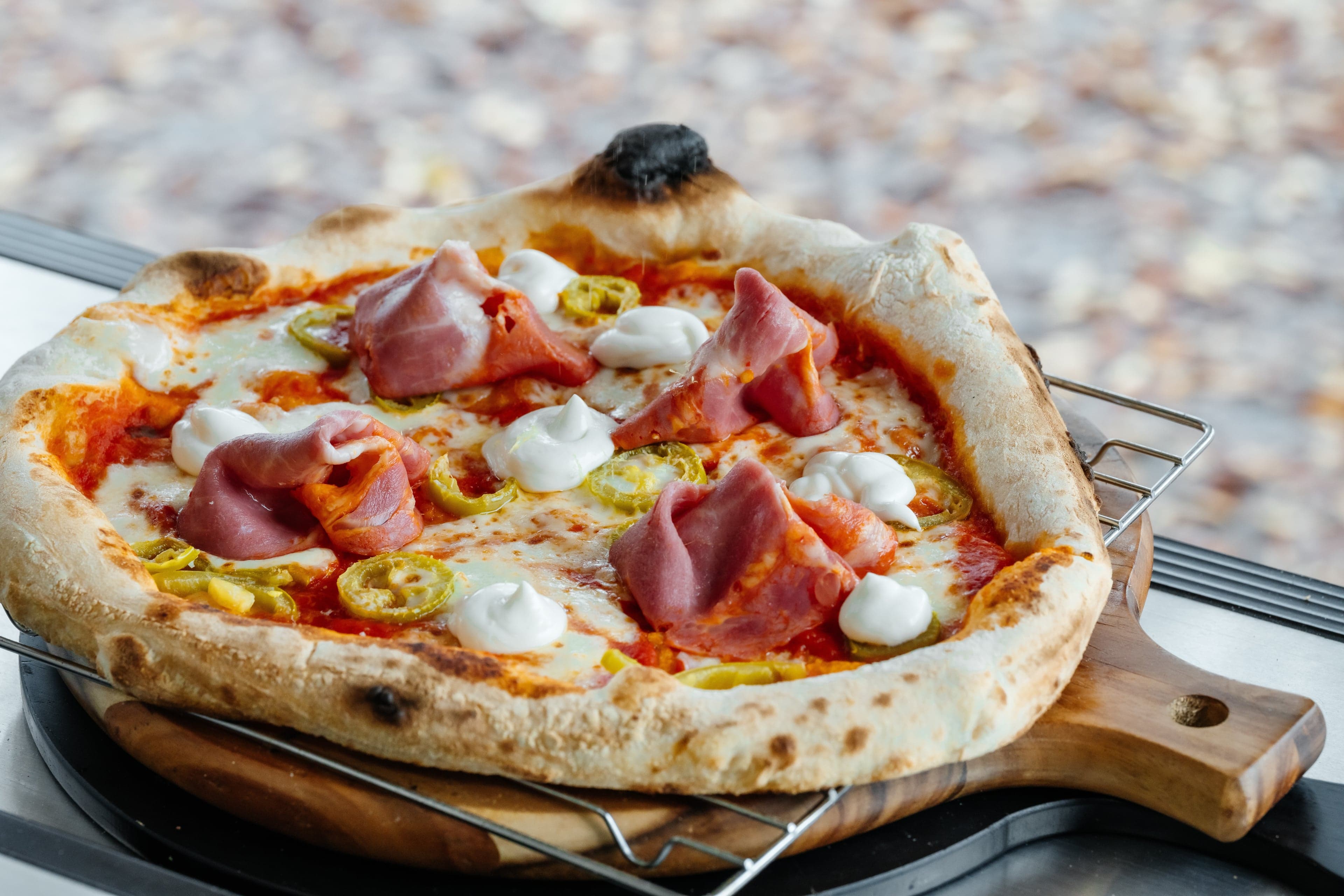 Wood-fired pizza with blistered crust and vibrant toppings served at an outdoor event