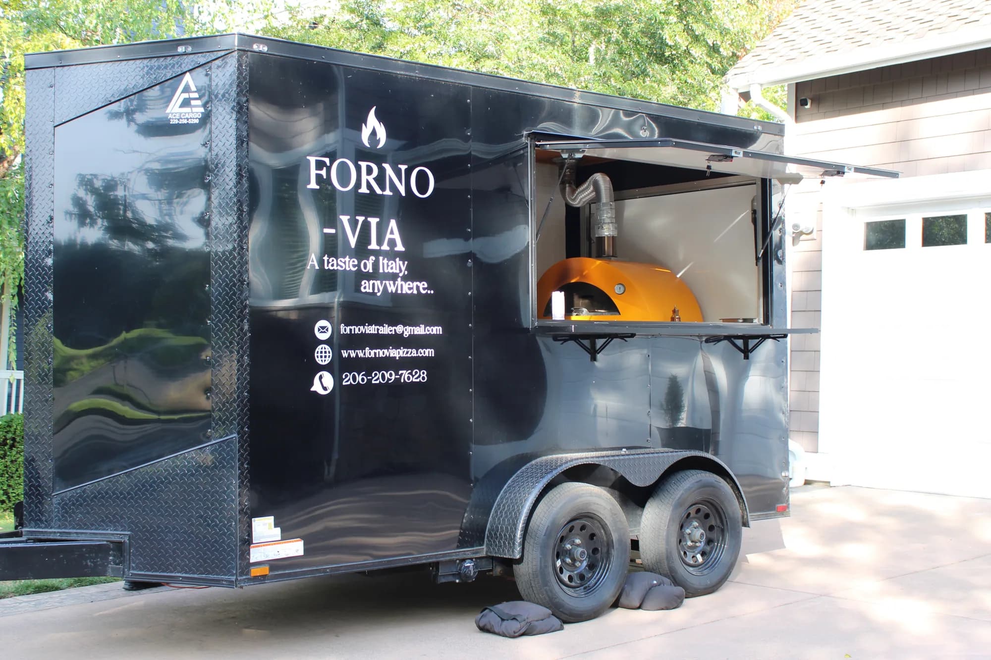 Forno Via’s black mobile pizza trailer ready to serve at a private event